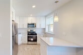 Located at 188 Bellevue Avenue in the desirable community of Montclair, NJ, this well-appointed one-bedroom, one-bathroom residence offers a thoughtfully designed layout across a single floor. Rich hardwood flooring flows throughout the living areas and bedroom, complemented by crisp white trim, crown molding, and recessed lighting that create a clean, polished aesthetic.

The living room is generously proportioned, bathed in natural light from multiple double-hung windows that frame views of the surrounding neighborhood's lush greenery. Baseboard radiators provide efficient heating throughout. The bedroom offers a comfortable footprint with two built-in closets featuring wire shelving systems, delivering ample storage, and windows that invite additional natural light.

The kitchen stands out as a modern highlight, outfitted with white shaker-style cabinetry, light quartz countertops, stainless steel appliances including a gas range and microwave, light hardwood-style flooring, a peninsula with pendant lighting, and a window for natural ventilation — ideal for both everyday cooking and casual dining.

The bathroom is finished with clean white subway tile surrounding a tub and glass sliding shower door, offering a timeless and functional design. Two hallways connect the spaces efficiently, adding to the overall flow of the residence. This home combines classic architectural charm with modern updates throughout.