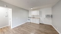 Located at 1830-1840 W Commonwealth Ave in Fullerton, CA, this one-bedroom, one-bathroom unit offers a thoughtfully arranged single-floor layout that makes efficient use of its compact footprint. The open-concept kitchen and living area serves as the heart of the home, featuring light wood-look flooring, soft gray walls, and a textured ceiling throughout. The kitchen is outfitted with crisp white cabinetry, granite-style countertops, a gas range, and a single-basin sink — all arranged along one wall to maximize the openness of the shared living space. A wall-mounted AC unit provides climate control. The bedroom is a comfortable, private retreat with a ceiling fan with light fixture, a large window dressed with vertical blinds that invites natural light, and access to a dedicated closet. The bathroom is finished with large-format neutral tile surrounding a full soaking tub and shower combination, complemented by a white vanity with a clean countertop. A hallway connects the rooms, adding a sense of separation and flow throughout the unit. The consistent use of light tones and wood-look flooring creates a cohesive, clean aesthetic throughout the entire space.