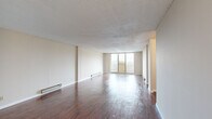 Located at 2000 Sixth Ave in Troy, NY, this two-bedroom, one-bathroom residence offers a practical and well-organized single-floor layout. Rich, dark hardwood flooring flows consistently throughout the space, complementing the neutral tones of the walls and creating a warm, cohesive aesthetic. The generous living room is a standout feature, offering ample open space, a textured ceiling, baseboard heating, and a large sliding glass door that opens to a balcony with outdoor views, flooding the room with natural light. The galley-style kitchen is efficiently designed with warm wood cabinetry, granite-style countertops, a double sink, and black appliances including a refrigerator and range. Both bedrooms are comfortably sized, with the primary bedroom offering a spacious layout, natural light from a window, and a full-width built-in closet with bifold doors. The second bedroom also features hardwood floors, a window, and baseboard heating. The bathroom is clean and functional, featuring a full-size soaking tub with an overhead shower, a white vanity with sink, and bright white finishes. A hallway and entrance area complete the layout, providing a smooth flow between all rooms.