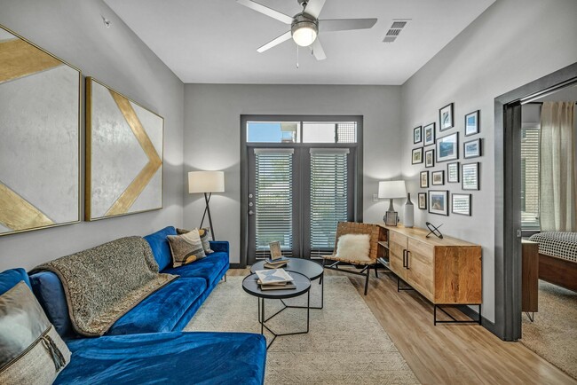 Living room with wood-inspired flooring leading out to the balcony - The Brick and Mortar District Apartments