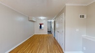 Located at 2637 Berkshire Rd in Augusta, Georgia, this two-story home offers a well-defined layout across both levels, blending practical design with comfortable living spaces. The main level is distinguished by warm hardwood flooring that extends throughout the primary living areas, complemented by crown molding and neutral-toned walls that create a clean, cohesive aesthetic. A spacious living area features a ceiling fan, textured ceiling, and large windows dressed with sheer curtains that allow natural light to fill the room while offering views of the outdoor surroundings. An interior pass-through window connects the living space to an adjacent area, adding a functional architectural detail. The kitchen is a notable feature, showcasing rich wood cabinetry that extends to the ceiling, dark granite-style countertops, a stainless steel sink, and appliances including an electric range, built-in microwave, and refrigerator. Tile flooring grounds the kitchen space. A staircase connects the main level to the upper floor, where carpeted bedrooms provide a softer, quieter environment. These rooms offer closet access and multiple doorways, with at least one bedroom benefiting from natural light through a wide window. Throughout both floors, six-panel doors and white baseboards maintain a consistent, tidy finish.