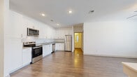This single-floor residence offers a thoughtfully designed layout spanning two bedrooms, two bathrooms, a combined kitchen and living area, two closets, and a dedicated laundry room. The open-concept kitchen and living space serves as the heart of the home, featuring wood-look flooring throughout, recessed lighting, and a ceiling fan in the living area. The kitchen is outfitted with crisp white shaker-style cabinetry, granite-look countertops, and a full suite of stainless steel appliances including a refrigerator, range, microwave, and dishwasher. A breakfast bar connects the kitchen to the living space, enhancing the open flow.

Both bedrooms are carpeted and equipped with ceiling fans. The primary bedroom offers a generous footprint with direct access to a walk-in closet fitted with multi-level wire shelving. The second bedroom features a large window that invites natural light. Each bathroom is finished with wood-look flooring, a white vanity with stone-look countertops, and a tub-shower combination. The dedicated laundry room houses a full-size washer and dryer. Additional storage is provided by a second carpeted closet with wire shelving. The space presents a clean, modern aesthetic throughout with a neutral color palette.