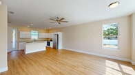 Located at 216 S Florida Ave in DeLand, FL, this two-story unit offers 3 bedrooms and 3 bathrooms across two well-proportioned floors. The main level hosts an open kitchen and living area bathed in natural light from large windows. The kitchen is a standout feature, showcasing crisp white shaker cabinetry, light stone countertops, a central island, and a full suite of stainless steel appliances including a range, dishwasher, and refrigerator. Light hardwood flooring flows throughout both levels, lending warmth and continuity to the space. The living room is bright and airy, with large windows framing outdoor views and a ceiling fan for added comfort. French doors in one room open to an outdoor balcony, enhancing the connection to the outside. The upper floor houses the three bedrooms, each finished with the same warm hardwood floors and windows offering natural light and neighborhood views. The primary bedroom includes French door balcony access. Three clean, well-appointed bathrooms feature white vanity cabinetry, stone-topped counters, and light tile flooring. A dedicated hallway, staircase, and closet round out this functional and attractively finished multi-level home.