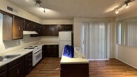 This single-floor residence offers a practical and comfortable layout designed for everyday living. The kitchen serves as a functional hub, featuring rich dark wood cabinetry, white appliances including a range, dishwasher, and refrigerator, as well as a double-basin sink and hardwood-style flooring. A central island provides additional counter space, while a sliding glass door brings in natural light and connects the kitchen to the exterior. Track lighting overhead ensures the workspace is well-illuminated.

The living area is open and spacious, anchored by a fireplace that adds a focal point to the room. Textured ceilings are consistent throughout the unit, lending a classic residential character to each space.

The bedrooms are carpeted and generously sized, each equipped with a ceiling fan and light fixture. Natural light filters in through windows fitted with blinds. The primary bedroom includes direct access to a private en-suite bathroom as well as a walk-in closet, offering convenient storage. Additional bedrooms provide closet access and share a hallway bathroom.

Throughout the unit, neutral wall tones and light carpeting create a clean, versatile backdrop suitable for a variety of furnishing styles. The straightforward single-floor plan ensures easy navigation and accessibility across all rooms.