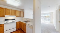 Located at 13430 Coppermine Rd in Herndon, Virginia, this single-floor residence offers a clean, functional layout designed for comfortable everyday living. The kitchen is equipped with warm oak cabinetry, light-toned countertops, a white electric coil range with an overhead ventilation hood, a built-in dishwasher, and a stainless steel sink. A pass-through window connects the kitchen to the living area, enhancing the open feel of the space. The living area is generously sized, featuring plush wall-to-wall carpeting and a sliding glass door fitted with vertical blinds that lead to a balcony, allowing abundant natural light to pour in. The bedrooms continue the carpeted flooring theme and are bright, airy spaces with large windows dressed in horizontal blinds that frame views of the surrounding landscape. The bathrooms feature wood-toned vanity cabinetry, light countertops, large mirrors, and hardwood-style flooring, offering a clean and practical design. Throughout the residence, the neutral white walls and light-toned finishes create a cohesive, understated aesthetic that provides a versatile backdrop for personalization.