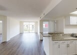 Located at 18335 NW 68 Ave in Hialeah, FL, this single-floor unit offers a thoughtfully designed open layout that seamlessly connects the living, dining, and kitchen areas. Rich hardwood-style flooring runs throughout the main living spaces, complementing the clean white walls and textured ceilings. The living area is bright and airy, drawing in natural light through large sliding glass doors that open to a balcony with outdoor views.

The kitchen features crisp white cabinetry, granite countertops, a functional peninsula with a built-in sink, and stainless steel appliances including a side-by-side refrigerator and dishwasher. A dedicated laundry area with stacked washer and dryer units is conveniently tucked within the kitchen corridor.

Two well-proportioned bedrooms each offer hardwood-style flooring, large windows with views of the surrounding community, and generous closet space. The primary bathroom includes a glass-enclosed walk-in shower with decorative tile accenting, a granite-topped vanity, and a large mirror. A second full bathroom provides a tub and shower combination with sliding glass doors, a granite vanity, and tile flooring. A pendant light fixture and electrical panel are also present in the secondary bedroom hallway area, adding functional detail to the overall design.