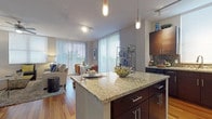 This stylish single-floor residence offers a thoughtfully designed open-concept layout that seamlessly connects the kitchen, dining, and living areas. The gourmet kitchen is outfitted with dark espresso cabinetry, granite countertops, a mosaic tile backsplash, and a full suite of stainless steel appliances, including a French door refrigerator, range, microwave, and dishwasher. Track lighting and elegant pendant lights illuminate the space, while a breakfast bar with bar seating provides a casual dining option. Rich hardwood flooring flows throughout the main living areas, anchoring the open dining space, which features large windows with vertical blinds that invite natural light. The living room is generously sized, with a ceiling fan, multiple windows, and glass sliding doors leading to a private balcony with outdoor views. The primary bedroom is carpeted and tranquil, with direct access to a luxurious en-suite bathroom featuring a dual-sink granite vanity, a soaking tub, and large-format tile flooring. A second bathroom mirrors the refined finishes with dark cabinetry and granite countertops. A bold teal accent wall in the living and dining areas adds a contemporary design element throughout, creating a vibrant yet cohesive ambiance.