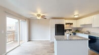 This well-organized 3-bedroom, 1-bathroom unit is thoughtfully laid out across a single floor, making efficient use of its compact footprint. The open-concept living and kitchen area serves as the heart of the home, where neutral-toned carpet flows through the living space and transitions to light wood-style flooring in the kitchen. A ceiling fan with light fixture anchors the combined living area, which is brightened by a large sliding glass door leading to a private balcony and a vertical-blind covered window that allows ample natural light.

The kitchen is outfitted with crisp white cabinetry, granite-style countertops, a black refrigerator, electric range, dishwasher, and a peninsula that separates the cooking area from the living space. All three bedrooms feature carpeted floors, neutral warm-toned walls, and windows that bring in natural light. The bedrooms include baseboard heating and closets with sliding doors and built-in shelving. Textured ceilings are present in select rooms.

The single full bathroom includes a white vanity with under-cabinet storage, a toilet, and a tub-shower combination with a curtain rod, set on wood-style flooring. The overall aesthetic is clean, functional, and well-maintained, offering practical living with a comfortable, neutral palette throughout.