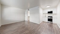 Studio 26 at 241 S Olive in Alhambra, California offers a thoughtfully designed single-floor layout that maximizes functionality and comfort. The main living area is open and airy, finished with durable wood-style plank flooring that runs throughout the space, creating a cohesive and modern aesthetic. Crisp white walls reflect natural light that streams in through a large horizontal window fitted with blinds, lending the room a bright and welcoming atmosphere. A wall-mounted HVAC unit ensures year-round climate control.

A dedicated kitchenette area is neatly tucked along one wall, featuring white cabinetry and an integrated sink, providing efficient use of space without compromising the open feel of the main room. An interior door leads to a generously sized walk-in closet outfitted with built-in shelving and drawers, offering ample storage and organization options.

The bathroom is clean and well-appointed, showcasing a white vanity with a marble-style countertop, an undermount sink, brushed nickel hardware, and a mirrored medicine cabinet above. The overall design of Studio 26 emphasizes a neutral, minimalist palette throughout, making it a versatile and move-in ready space located in the heart of Alhambra.