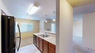 Located at 15913 E Fourth Ave in Spokane Valley, Washington, this 2-bedroom, 1-bathroom residence offers a practical and well-organized single-floor layout. The kitchen serves as a central hub of the home, featuring rich warm-toned cabinetry, a double-basin sink, a dishwasher, and light countertops. Elegant pendant lights hang over the kitchen pass-through, while a skylight-style flush fixture provides bright overhead illumination. The kitchen opens toward the living area, creating a connected, social atmosphere. Natural light filters throughout from multiple windows fitted with horizontal blinds. Both bedrooms are carpeted and finished with neutral warm tones, each featuring a window that allows in natural light. The bedrooms are serviced by two closets, providing ample storage. The bathroom includes a full tub and shower combination, a toilet, tile flooring, and a baseboard heater. A connecting hallway links the main living areas to the private quarters. The unit also features a six-panel interior door and an electrical panel, reflecting thoughtful functional design. The overall ambiance is clean, neutral, and move-in ready, suited for comfortable everyday living in the Spokane Valley community.