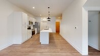 This two-story home offers a thoughtfully laid-out floor plan across two levels of comfortable living space. The main floor features an open-concept kitchen and living area with durable wood-look flooring, recessed lighting, and a striking kitchen island with an integrated sink topped by a white countertop. White cabinetry pairs with stainless steel appliances and a herringbone tile backsplash, while two pendant lights add a modern industrial touch. A convenient half-bath with a pedestal sink and wood-look tile flooring is also located on the main level.

A carpeted staircase with a clean white railing leads to the upper floor, where two bedrooms and two full bathrooms are found. The primary bedroom offers a walk-in closet with wire shelving, providing ample storage. Both bedrooms feature plush carpet, natural light through slatted blinds, and neighborhood views. The full bathrooms include a tub-shower combination with a curved rod and light hardwood-style flooring. A dedicated laundry room on the upper level houses a full-size washer and dryer. Two hallways connect the spaces efficiently, and two closets ensure excellent storage throughout this clean, move-in-ready home.