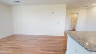 This single-floor residence in Lebanon, Indiana offers a thoughtfully designed layout with two bedrooms and two full bathrooms. Warm hardwood-style flooring runs consistently throughout the unit, creating a cohesive and clean aesthetic in every room.

The open-concept kitchen and living area serves as the central hub of the home. The kitchen is well-equipped with stainless steel appliances, including a refrigerator, range, microwave, and dishwasher. White shaker-style cabinetry with sleek hardware lines the walls, complemented by granite countertops and a subway tile backsplash. A central island with granite countertop provides additional prep space and casual seating. Pendant lighting and recessed ceiling lights illuminate the area, while multiple windows invite natural light into the combined living space.

The spacious primary bedroom features multiple windows with neighborhood views and a ceiling fan. Its en-suite bathroom includes a granite-topped vanity with white cabinetry and a glass-door walk-in shower, alongside a dedicated walk-in closet with wire shelving. The second bathroom mirrors the same refined finishes, with a granite vanity and access to an additional closet. The second bedroom is bright and well-proportioned, also featuring a ceiling fan and exterior views.