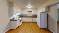 This single-floor unit offers a practical and comfortable layout with a variety of living spaces connected by hardwood-style flooring throughout the main areas. The entry hallway provides a clean, welcoming transition into the home, with easy access to the surrounding rooms.

The kitchen is well-equipped with ample white cabinetry, dark laminate countertops, and white appliances including a range, dishwasher, and refrigerator. The hardwood-style flooring continues here, adding warmth and easy maintenance to the space.

The living area is generously proportioned, featuring large windows with vertical blinds that allow for natural light while maintaining privacy. The open feel is enhanced by neutral wall tones and smooth, light-reflecting flooring.

The bedrooms are carpeted for comfort and each features a ceiling fan with integrated lighting. Windows with horizontal blinds allow for controllable natural light in each room.

The bathroom includes a tiled tub and shower combination with warm-toned wall tiles, while a separate vanity area features a white undermount sink, updated brushed nickel faucet, white tile backsplash, and a large mirror. Throughout the unit, neutral color palettes, textured ceilings, and consistent finishes contribute to a cohesive and functional living environment.