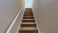 This thoughtfully designed 2-bedroom, 2-bathroom home offers a comfortable and functional layout across a single floor. The living room is a welcoming centerpiece, featuring a classic white-mantled fireplace, crown molding, a ceiling fan, and large windows that flood the space with natural light and views of the surrounding trees. Plush carpeting flows throughout the living and dining areas, adding warmth to the neutral, beige-toned palette.

The kitchen is well-equipped with light wood cabinetry, granite-style countertops, hardwood-style flooring, a stainless steel range, and a dishwasher. A bright dining nook adjacent to the kitchen benefits from large corner windows that bring in ample sunlight.

The primary bedroom is generously sized, with a ceiling fan, carpeted flooring, and access to a dedicated bathroom featuring a wide vanity with dual sinks, granite-style countertops, and a walk-in closet with built-in shelving. The second bedroom is equally comfortable, offering a ceiling fan, plush carpet, and a bright window.

Additional highlights include a carpeted staircase with clean white trim, a hallway connecting key rooms, and two closets providing practical storage. A French door in the dining area leads to an outdoor space, completing this inviting home.