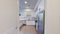 Located at 1012 Burnett St in downtown Fort Worth, Texas, this one-bedroom, two-bathroom unit offers a well-designed single-floor layout with a clean, contemporary aesthetic throughout. The kitchen is a standout feature, showcasing white shaker cabinetry with matte black hardware, granite countertops, a classic subway tile backsplash, and stainless steel appliances including a dishwasher, range, and refrigerator. A peninsula with pendant lighting adds both functionality and style, while light wood-look flooring completes the modern look. The bedroom is a comfortable retreat with soft carpeting, neutral walls, and a window that invites natural light. It connects to a spacious walk-in closet outfitted with multiple clothing rods and built-in shelving, providing ample storage. The two bathrooms are finished with tile and granite surfaces; one includes a soaking tub and shower combination with tiled surround and a built-in niche. A dedicated in-unit laundry area with a stacked washer and dryer adds everyday convenience. Throughout the space, the consistent use of white tones, neutral carpeting, and light flooring creates a bright, cohesive atmosphere well-suited for comfortable urban living.