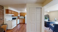 Located at 4363 Chestnut Ridge Rd in Buffalo, NY, this single-floor residence offers a thoughtfully organized layout encompassing a combined kitchen and living room, a dedicated office, one bedroom, and one full bathroom. The kitchen is outfitted with warm honey-toned wood cabinetry, stone-look countertops, a full suite of white appliances including a coil-top range and refrigerator, and durable hardwood-style flooring that extends into the adjacent living areas. The living room features the same rich flooring, complemented by a striking exposed brick accent wall visible from the open passageway, creating a warm and characterful ambiance. A dedicated office space provides a functional work-from-home environment with natural light streaming through a large window and a sliding glass door that opens to outdoor views. The spacious primary bedroom is finished with plush carpeting, a generous double-closet wall with sliding panel doors, and a bright window overlooking greenery. The full bathroom includes a tub-shower combination with clean white finishes. Throughout the residence, neutral wall tones and consistent finishes contribute to a cohesive, calm, and functional living environment.