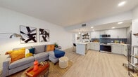 Located at 245 Bonita Glen Dr in Chula Vista, CA, this single-floor residence offers a thoughtfully designed open-concept layout finished with light wood-style flooring throughout. The living area is bright and welcoming, featuring large windows with roller shades that allow ample natural light, a sliding glass door to the exterior, and recessed lighting that complements the clean white walls.

The kitchen is a standout feature, showcasing white shaker cabinetry, a bold blue mosaic tile backsplash, stainless steel appliances, open shelving, and a central island with a white quartz countertop and bar seating — ideal for casual dining or entertaining. Pendant lights hang above the island, adding a modern finishing touch.

The bedroom is generously sized, complete with a ceiling fan, mirrored sliding closet doors, and light wood-style flooring that continues from the main living area. Two well-appointed bathrooms serve the home, each featuring white vanities with quartz countertops, large backlit mirrors, and tub-shower combinations with clean tile surrounds. One bathroom includes convenient built-in shelving for additional storage.

The overall ambiance is contemporary and cohesive, with a neutral palette punctuated by modern fixtures, creating a comfortable and functional living environment.