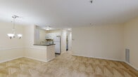 Located at 9100 Stebbing Way in Laurel, Maryland, this single-floor residence offers a well-organized layout with a neutral, light-filled interior throughout. The open-concept living and dining area is finished with plush wall-to-wall carpeting and warm beige tones, creating a calm and cohesive atmosphere. Large sliding glass doors lead directly to a private balcony overlooking greenery, while additional windows along the front of the unit allow natural light to flow freely into the space.

The kitchen is positioned at the heart of the unit and features a peninsula with dark granite-style countertops, a stainless steel sink, white cabinetry, and white appliances including a range, microwave, and refrigerator. Tile flooring grounds the kitchen area, providing a practical contrast to the carpeted living spaces.

The bedrooms are generously proportioned, carpeted, and include windows with outdoor views of surrounding trees, contributing to a quiet and private feel. The bathroom includes a white vanity with an integrated sink, a mirrored medicine cabinet, and tile flooring. A dedicated utility room houses a full-size washer and dryer alongside a water heater, adding significant day-to-day convenience to the unit.
