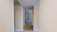 This 1,050-square-foot, single-story apartment at Red Stone Ranch in Cedar Park offers a practical and well-designed layout across 2 bedrooms, 2 bathrooms, and 3 closets. The combined kitchen and living room serves as the heart of the unit, featuring light wood cabinetry with crown molding details, white countertops, stainless steel appliances including a refrigerator, range, microwave, and dishwasher, and wood-look flooring. A built-in shelving nook and a dedicated desk area add functional storage and workspace options. The living area is carpeted and features a ceiling fan and an exterior door with adjacent windows that invite natural light and outdoor access. Both bedrooms are carpeted and equipped with ceiling fans; the primary bedroom measures 170 square feet and features crown molding and a large window with blinds. Each bedroom is supported by a well-sized closet with wire shelving systems. The two bathrooms are identically appointed with a tub-shower combo featuring white tile surround, wood-look flooring, a vanity with warm wood cabinetry, and a large mirror. A spacious walk-in closet with multi-tier wire shelving provides ample storage. Neutral tones throughout create a clean, cohesive ambiance.