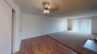 This single-story residence offers a practical and comfortable layout across several well-defined living spaces. The expansive main living area is a standout feature, combining wood-style flooring with plush carpeting and anchored by a striking tile-surround fireplace. A ceiling fan light fixture overhead adds functionality, while vertical blinds along one wall allow for natural light control. Built-in shelving near the entry provides convenient storage.

The galley-style kitchen is efficiently designed, featuring warm honey-toned wood cabinetry lining both walls, light countertops, a double sink, and white appliances including a range and refrigerator. The layout maximizes counter and cabinet space, making it highly functional for everyday use.

The bedrooms are carpeted for comfort, each featuring windows fitted with horizontal blinds that bring in natural light. Closet space is provided in the bedrooms for ample storage.

Two bathrooms serve the unit. Both feature wood-toned vanity cabinetry, light countertops, and framed mirrors. One bathroom includes a tub-shower combination with large-format tile surround, while the other offers a similarly appointed vanity with wood-style flooring and a decorative area rug. Textured ceilings are consistent throughout the space, contributing to a cohesive finish.