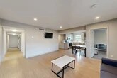 Located at 126 College Ave in Ithaca, NY, this single-floor, six-bedroom, three-bathroom home offers a functional and modern layout well-suited for group living. The open-plan living area flows seamlessly into the kitchen and dining space, featuring light hardwood-style flooring, recessed ceiling lights, and a wall-mounted TV. The kitchen is equipped with stainless steel appliances — including a refrigerator, dishwasher, and electric range — white cabinetry, ample counter space, and a window that brings in natural light. A long, well-lit hallway connects the shared spaces to the six private bedrooms, each finished with neutral-toned walls, carpet flooring, and a built-in desk and chair, providing a practical setup for studying or working. Three bathrooms serve the residence, each clean and efficiently designed with light flooring and shower-tub combinations. The home maintains a cohesive, modern aesthetic throughout, with neutral grey and white tones, clean lines, and consistent finishes. A dedicated closet and hallway provide additional storage and circulation space, rounding out this well-organized and spacious residence in the heart of Ithaca.