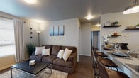 Located at West Elm Avenue in Stillwater, Oklahoma, this single-story unit offers a thoughtfully designed layout that balances communal living with private spaces. The open-concept living area features warm wood-look flooring, neutral-toned walls, and large windows that allow ample natural light to fill the room. A comfortable seating area flows naturally toward the dining space, creating an inviting atmosphere for both relaxing and entertaining.

The kitchen is equipped with dark cabinetry, black appliances including a refrigerator, range, and microwave, and a granite-topped island that doubles as a breakfast bar with bar seating. A pendant light above the island adds a modern touch, while the adjacent entry door provides convenient access.

Each bedroom is generously sized, with wood-look flooring, windows with natural light, and dedicated space for both sleeping and studying. The rooms reflect a functional and comfortable design suited for everyday living.

The unit includes two bathrooms, each featuring dark vanity cabinetry topped with granite countertops, large mirrors, and wood-look flooring. One bathroom includes a full tub-shower combination, while the other features a granite-topped vanity with ample counter space. Together, these spaces offer a clean, cohesive aesthetic throughout the unit.