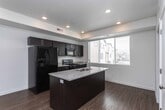 Located in West Jordan, Utah, this three-story home offers a clean, modern aesthetic defined by crisp white walls, wood-style flooring, and an open, airy layout throughout its multiple levels. The entry level welcomes residents with a bright, open living area bathed in natural light from large windows, with smooth flooring and a staircase connecting the floors seamlessly.

The kitchen is a functional centerpiece, featuring dark espresso cabinetry, granite-style countertops, and a central island with an undermount sink. Black appliances—including a side-by-side refrigerator, gas range, and over-the-range microwave—complement the bold cabinetry contrast. Recessed lighting and generous window placement keep the space bright and inviting.

Carpeted bedrooms provide a comfortable retreat, each featuring neutral tones and windows that bring in natural light. The bathrooms continue the home's cohesive design language, outfitted with dark vanity cabinets, granite-topped counters, large mirrors, and wood-style flooring. One bathroom includes a tub-shower combination with a curved curtain rod.

A dedicated laundry room with full-size washer and dryer adds everyday convenience. Carpeted stairs with a metal handrail connect all three levels, reinforcing the home's practical and well-designed layout.