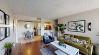 This well-appointed single-floor residence offers a thoughtfully designed open-concept layout that seamlessly connects the living, dining, and kitchen areas. The living room is anchored by warm hardwood-style flooring, a textured ceiling, and a sliding glass door that opens to a private outdoor space, allowing natural light to fill the room. The space is complemented by curated wall art and contemporary furnishings that give the interior a modern, mid-century aesthetic.

The kitchen is both functional and visually appealing, featuring white shaker cabinetry, a classic subway tile backsplash, stainless steel appliances including a refrigerator and range, and a pass-through bar counter that connects to the living area—ideal for casual dining or entertaining. The adjacent dining area is cozy and well-lit, enhanced by a ceiling fan with integrated lighting.

The bedroom is a comfortable retreat with hardwood-style flooring, a bright window that invites natural light, and ample space for both sleeping and a dedicated workspace. The bathroom is clean and straightforward, offering a full shower-tub combination. Throughout the residence, neutral tones and consistent flooring create a cohesive, inviting ambiance.