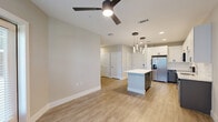 This well-appointed one-bedroom, one-bathroom residence in Sanford, Florida offers a thoughtfully designed layout across a single floor. The open-concept living and kitchen area serves as the heart of the home, featuring wood-look flooring, a ceiling fan, and large windows that fill the space with natural light. A sliding glass door leads to a private patio framed by black metal railings, overlooking a lushly landscaped courtyard complete with palm trees, a pool, and lounge seating.

The kitchen is a standout feature, showcasing two-tone cabinetry with crisp white upper cabinets and slate-gray lower cabinets, all accented with matte black hardware. A quartz waterfall island anchors the space beneath elegant cluster pendant lighting, while a full suite of stainless steel appliances, including a French door refrigerator, range, microwave, and dishwasher, round out the functional design.

The spacious primary bedroom is finished with plush carpeting, soft neutral tones, a ceiling fan, and a window with outdoor views. The bathroom continues the refined aesthetic with marble-look tiled surround in the tub/shower combo, a gray vanity with quartz countertop, and a large framed mirror with modern lighting above.