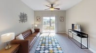 This single-floor residence offers a thoughtfully arranged layout with a variety of functional spaces throughout. The living room serves as a welcoming central hub, featuring plush carpeting, a ceiling fan with light fixture, and sliding glass doors that open onto a private balcony with outdoor seating and scenic views beyond.

Adjacent to the living area, the dining space features warm wood-look flooring, track lighting overhead, and enough room to comfortably accommodate a four-person table. The galley-style kitchen runs parallel along both walls, offering warm wood cabinetry, dark countertops, a double-basin sink, and black appliances including a range and refrigerator. A dedicated laundry room is conveniently accessible directly from the kitchen.

The residence includes multiple bedrooms, each finished with soft carpeting and natural light from windows with blinds. Mirrored sliding closet doors add a sense of depth to the rooms. Both bathrooms are finished consistently with wood-look flooring, white cabinetry, a single vanity with mirror, and well-lit overhead fixtures. One bathroom includes a shower-tub combination, while the other features a standalone shower configuration.