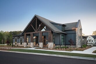 Clubhouse exterior with ample parking and rocking chairs on the front porch. - The Bend at Pettit Creek