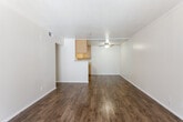This single-story unit located in Anaheim, California offers a well-organized layout with distinct living, kitchen, and sleeping areas. The main living space is open and generously sized, featuring warm-toned wood-look flooring that extends throughout the common areas. Crown molding lines the ceiling, adding a clean, finished detail, while a ceiling fan with a light fixture provides both comfort and illumination. A sliding glass door and an adjacent entry door allow natural light to fill the living area, creating a bright and airy atmosphere.

The kitchen opens to the living space via a half-wall pass-through, making it feel connected yet defined. It is equipped with honey-toned wood cabinetry offering ample upper and lower storage, a gas range, dishwasher, and a double sink with a window above. The wood-look flooring continues into this space, maintaining visual continuity.

The bedrooms are carpeted and offer a quieter, softer feel. Each room receives natural light through windows fitted with vertical blinds. One bedroom features mirrored sliding closet doors, enhancing the sense of space. A hallway connects the bedrooms to the bathroom, providing a practical and private corridor within the unit.