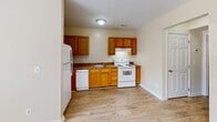 This single-floor, one-bedroom, one-bathroom unit in Orange, Virginia offers a practical and efficiently designed layout. The kitchen is a functional space equipped with warm oak cabinetry, dark laminate countertops, and white appliances including a refrigerator, electric range, dishwasher, and a built-in range hood. Light hardwood-style flooring runs throughout the kitchen area, contributing to a clean and cohesive look.

The bedroom is a comfortably sized room featuring soft wall-to-wall carpeting and neutral cream-toned walls. A window allows natural light to filter in, providing views of the surrounding greenery. The room includes baseboard heating and is finished with clean white trim throughout.

The full bathroom is accessed through a white paneled door and features a shower/tub combination with a curtain rod, a toilet, and hardwood-style flooring that matches the rest of the unit. The bathroom's compact design makes efficient use of the available space.

Overall, the unit presents a straightforward, functional aesthetic with neutral tones, consistent flooring materials, and practical finishes throughout. Its modest footprint makes it a manageable and low-maintenance living space suitable for a single occupant or couple.