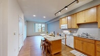 Located at 4729 Grand Ave NE in Columbia Heights, Minnesota, this one-bedroom, one-bathroom residence offers a thoughtfully designed single-floor layout that maximizes every square foot of its compact footprint. The open-concept kitchen and living area serves as the heart of the home, where warm maple cabinetry, granite countertops, and a central island with bar seating create a functional and inviting space. Track lighting overhead illuminates the kitchen, which features white appliances including a range, microwave, dishwasher, and refrigerator. Hardwood-style flooring flows throughout the main living areas, adding warmth and continuity. Large windows in the living room flood the space with natural light and offer views of the surrounding neighborhood. The bedroom is a quiet retreat finished with plush carpeting and clean, neutral walls, providing a comfortable and restful environment. The full bathroom features a combination tub and shower, a single-sink vanity with maple cabinetry, and hardwood-style flooring. Additional practical features include a dedicated laundry area and four closets, offering generous storage throughout. The overall ambiance is clean, modern, and move-in ready.