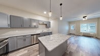 Located at 2988 Radio Rd in River Falls, WI, this single-story, 3-bedroom, 2-bathroom home offers a thoughtfully designed open-concept layout with modern finishes throughout. The kitchen is a standout feature, showcasing gray shaker-style cabinetry, a granite-topped center island, stainless steel appliances including a refrigerator, range, microwave, and dishwasher, and pendant lighting that adds a contemporary touch. Light wood-look luxury vinyl plank flooring flows through the main living areas, complementing the neutral color palette and creating a bright, cohesive aesthetic. The living area is accessed directly from the kitchen and entry, offering an airy, connected feel with natural light from multiple windows. The spacious primary bedroom features plush carpeting, a ceiling fan, and a walk-in closet outfitted with wire shelving and hanging rods for ample storage. The additional bedrooms are well-sized with carpet flooring, ceiling fans, and built-in closet storage. The bathrooms are clean and functional, with one featuring a full tub/shower combo and wood-look flooring. A dedicated hallway connects all rooms efficiently, completing this well-organized and move-in-ready home.