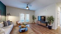 This single-story residence features 2 bedrooms and 2 bathrooms arranged across a practical, well-connected floor plan that includes a kitchen, living room, hallway, and closet. The living room serves as the heart of the home, showcasing warm hardwood-style flooring, a ceiling fan with light fixture, and a bold teal accent wall that adds a striking design element. French doors with shuttered windows invite abundant natural light and open to an outdoor area, enhancing the room's airy feel. The kitchen is outfitted with white shaker cabinetry, stainless steel appliances including a range, microwave, and refrigerator, complemented by white subway tile backsplash and light countertops — a clean, modern aesthetic throughout. Both bathrooms mirror each other in style, featuring large-format gray tile flooring, white subway-tiled tub-surround showers, white vanity cabinetry with gray countertops, and matte black hardware accents. The primary bedroom is generously sized with plush carpeting, a large window for natural light, and warm neutral tones. The second bedroom features a rich terracotta accent wall, carpet flooring, and warm ambient lighting. A connecting hallway with hardwood-style flooring ties all rooms together seamlessly.