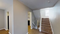 This three-story residence offers a well-organized layout across multiple levels, connected by a carpeted staircase that provides easy access throughout. The neutral-toned walls and consistent design language create a cohesive feel from floor to floor.

The kitchen is equipped with ample gray cabinetry, light countertops, and a full suite of black appliances, including a refrigerator, electric range, over-the-range microwave, and dishwasher. Wood-look flooring runs through the kitchen and hallways, providing a durable and easy-to-maintain surface.

The living area is generously sized, featuring plush carpeting, a window that allows natural light to filter in, and a sliding glass door that opens to an outdoor area. A carpeted hallway connects the main living spaces to additional rooms throughout the unit.

The bedrooms are comfortable and well-lit, each featuring soft carpeting, neutral walls, and windows with blinds. One bedroom includes a ceiling fan for added comfort. Multiple bathrooms serve the space — one features a full soaking tub and shower combination with a large mirror, while a second bathroom offers a glass-enclosed stand-up shower, a vanity with storage, and wood-look flooring. Both bathrooms are finished in clean white tones with modern fixtures.