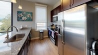 This well-appointed single-floor residence offers a thoughtfully designed open-concept layout with an inviting flow between the living, dining, and kitchen areas. The living room features light hardwood flooring, a wall-mounted fireplace, and a sliding glass door that opens to a private balcony, where sweeping views of the surrounding mountains and cityscape can be enjoyed. Floor-to-ceiling corner windows in the dining area flood the space with natural light, while a granite-topped kitchen island with bar seating connects seamlessly to the galley-style kitchen, which is outfitted with rich dark cabinetry, stainless steel appliances, a tile backsplash, and granite countertops.

The residence includes two comfortable bedrooms, each carpeted and equipped with ceiling fans, roller blinds, and ample storage. The primary bedroom offers a tranquil retreat with neutral tones and coordinated furnishings. Two bathrooms serve the home: one features a walk-in glass-enclosed shower with full-height dark tile surround and granite vanity, while the second includes a bathtub and tiled flooring with matching dark wood cabinetry. Throughout the home, a cohesive neutral color palette and modern finishes create a clean, contemporary ambiance well-suited for comfortable everyday living.