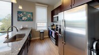 This well-appointed single-floor residence offers a thoughtfully designed open-concept layout with an inviting flow between the living, dining, and kitchen areas. The living room features light hardwood flooring, a wall-mounted fireplace, and a sliding glass door that opens to a private balcony, where sweeping views of the surrounding mountains and cityscape can be enjoyed. Floor-to-ceiling corner windows in the dining area flood the space with natural light, while a granite-topped kitchen island with bar seating connects seamlessly to the galley-style kitchen, which is outfitted with rich dark cabinetry, stainless steel appliances, a tile backsplash, and granite countertops.

The residence includes two comfortable bedrooms, each carpeted and equipped with ceiling fans, roller blinds, and ample storage. The primary bedroom offers a tranquil retreat with neutral tones and coordinated furnishings. Two bathrooms serve the home: one features a walk-in glass-enclosed shower with full-height dark tile surround and granite vanity, while the second includes a bathtub and tiled flooring with matching dark wood cabinetry. Throughout the home, a cohesive neutral color palette and modern finishes create a clean, contemporary ambiance well-suited for comfortable everyday living.