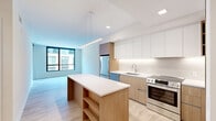 Located at 30 Ridge Square NW in Washington, DC, this thoughtfully designed one-bedroom, one-bathroom residence offers a clean, modern aesthetic throughout. Light-toned hardwood flooring flows seamlessly across the open-plan living and kitchen areas, enhancing the bright, airy ambiance.

The kitchen is a standout feature, showcasing a combination of white upper cabinetry and warm wood-toned lower cabinets with under-cabinet lighting. A center island with a white quartz countertop and built-in shelving provides both prep space and casual seating. Stainless steel appliances, including a refrigerator, range, and dishwasher, complete the well-appointed culinary space. A linear pendant light above the island adds a refined touch.

The living area benefits from large floor-to-ceiling windows that invite abundant natural light and urban views, with direct access to a private balcony. The bedroom is a serene retreat with its own large window, two closets—including a shelved walk-in—and light hardwood floors. The full bathroom features large-format neutral tile, a soaking tub with shower, and a floating wood-grain vanity with a white countertop. A hallway connects all spaces efficiently, completing this well-organized and stylish residence.
