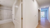 Located at 4200 N Carlin Springs Rd in Arlington, VA, this one-bedroom, one-bathroom unit offers a well-planned layout across a single floor. The combined living and dining area is bright and open, featuring light hardwood-style flooring, a ceiling fan, and a large window that fills the space with natural light and offers outdoor views. The kitchen is thoughtfully designed with gray cabinetry, white countertops, a subway tile backsplash, and a full suite of stainless steel appliances including a refrigerator with ice and water dispenser, range, built-in microwave, and dishwasher. A skylight adds additional brightness to the kitchen area. The bedroom is carpeted for comfort and includes a sliding-door closet, providing practical storage. A dedicated hallway closet offers additional storage space, and an in-unit laundry area adds everyday convenience. The bathroom is finished with large-format tile, a soaking tub with a tiled surround, matte black fixtures, and a gray vanity with a white countertop. Clean white walls and consistent finishes throughout give the unit a cohesive, modern feel.
