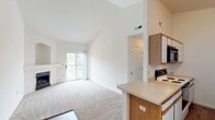 Located at 353 Autumn Creek Dr in Manchester, Missouri, this single-floor residence offers a thoughtfully designed layout with a clean, neutral palette throughout. The living area is a standout, featuring dramatic vaulted ceilings that amplify the sense of space and an elegant fireplace with an arched niche surround that serves as a natural focal point. Plush carpeting runs through the living and bedroom areas, while wood-style flooring defines the entryway and kitchen. A sliding glass door opens to a private balcony, inviting abundant natural light and outdoor views into the main living space. The galley-style kitchen is efficiently arranged with white cabinetry, oak-accented upper cabinets, light countertops, and a full suite of appliances including a range, microwave, dishwasher, and refrigerator. A peninsula counter provides a seamless transition to the living area. The bedrooms are carpeted and bright, with one featuring a sliding closet and a window overlooking the surrounding greenery. A hallway connects the private areas of the home, which include a bathroom with tile flooring and a soaking tub. Throughout, the space maintains a light, airy atmosphere complemented by high ceilings and a consistent, neutral color scheme.