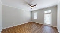 This single-story, one-bedroom, one-bathroom unit offers a thoughtfully designed layout that maximizes functionality across its living spaces. The living area features warm wood-look hardwood flooring, crown molding, and a ceiling fan with light fixture, creating a bright and comfortable atmosphere. Natural light filters in through blinded windows, while a private entry door adds convenience.

The kitchen is well-equipped with dark espresso cabinetry, granite-style countertops, and a full suite of stainless steel appliances, including a refrigerator, electric range, and microwave. A peninsula with pendant lighting connects the kitchen to the living area, enhancing the open flow of the space.

The bedroom is carpeted for comfort and includes a ceiling fan, a window with blinds for natural light, and ample wall space for furnishings. The bathroom features wood-look flooring, a granite-topped vanity with dark cabinetry, a combined tub and shower with a curved curtain rod, and clean neutral wall tones throughout.

Consistent neutral gray walls, white trim, and cohesive finishes across all rooms give this unit a clean, modern aesthetic.