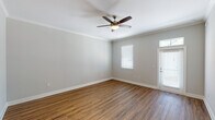 This single-story, one-bedroom, one-bathroom unit offers a thoughtfully designed layout that maximizes functionality across its living spaces. The living area features warm wood-look hardwood flooring, crown molding, and a ceiling fan with light fixture, creating a bright and comfortable atmosphere. Natural light filters in through blinded windows, while a private entry door adds convenience.

The kitchen is well-equipped with dark espresso cabinetry, granite-style countertops, and a full suite of stainless steel appliances, including a refrigerator, electric range, and microwave. A peninsula with pendant lighting connects the kitchen to the living area, enhancing the open flow of the space.

The bedroom is carpeted for comfort and includes a ceiling fan, a window with blinds for natural light, and ample wall space for furnishings. The bathroom features wood-look flooring, a granite-topped vanity with dark cabinetry, a combined tub and shower with a curved curtain rod, and clean neutral wall tones throughout.

Consistent neutral gray walls, white trim, and cohesive finishes across all rooms give this unit a clean, modern aesthetic.
