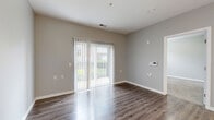 Located at 7600 Huntington Park Dr in Columbus, OH, this one-bedroom, one-bathroom unit offers a well-organized, efficiently designed single-floor layout. The combined kitchen and living area forms the heart of the home, featuring rich hardwood-style flooring that runs throughout the main spaces. A full-height sliding glass door dressed with vertical blinds fills the living area with natural light and provides a pleasant view of the surrounding greenery, creating an open and airy atmosphere. The kitchen is positioned adjacent to the living space and includes a pantry for added storage convenience. The bedroom is a comfortable, well-proportioned retreat finished with plush carpeting and neutral gray walls. It is complemented by a walk-in closet outfitted with wire shelving systems, offering ample organization options. A second closet provides additional storage. The bathroom features a walk-in shower with a grab bar and clean white surround. A dedicated laundry area and a utility room housing the water heater and HVAC equipment add to the unit's functionality. Throughout the space, neutral gray walls, white trim, and consistent flooring choices create a cohesive, modern aesthetic.