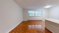 Located at 26 Park St E in Mississauga, this one-bedroom, one-bathroom unit offers a well-organized layout across a single floor. The space is immediately distinguished by its warm, polished parquet flooring, which flows consistently throughout the living, dining, and bedroom areas, adding a classic character to the interior.

The open kitchen is outfitted with modern stainless steel appliances, including a refrigerator and electric range, paired with contemporary light wood cabinetry and clean white countertops. A central dividing wall partially separates the kitchen from the adjoining living and dining areas, creating a sense of definition while maintaining an open feel. A large window in the living area allows natural light to brighten the space and offers a view of the surrounding greenery.

The bedroom is a comfortable, well-proportioned room featuring its own window with natural light and a mirrored sliding-door closet that visually expands the space. Additional storage is provided by three closets distributed throughout the unit.

The bathroom is a standout feature, showcasing elegant marble-style tile surrounds on the bathtub, complemented by a small privacy window that introduces natural light. The entrance and hallway provide a practical transition into the main living areas, completing this efficiently designed and thoughtfully appointed unit.