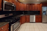 Located at 835 Broadway Ave in Holbrook, NY, this two-floor home offers a thoughtfully designed layout with consistent, quality finishes throughout. The kitchen serves as a functional centerpiece, showcasing rich cherry wood cabinetry, dark granite countertops with a complementary black tile backsplash, tile flooring, and a full suite of stainless steel appliances including a gas range, built-in microwave, dishwasher, and French door refrigerator — all illuminated by recessed lighting.

The carpeted living and bedroom spaces are finished with elegant crown molding and ceiling fans with integrated lighting. Sliding glass doors in multiple rooms invite natural light and provide outdoor access, while horizontal blinds and vertical window treatments offer privacy. Recessed lighting adds to the bright, welcoming atmosphere throughout.

The bathrooms are consistent in design, featuring rich cherry wood vanities topped with dark granite countertops and tile flooring. The full bathroom includes a tiled tub-shower combination with sleek sliding glass doors, while a half bath provides a convenient powder room.

The lower level presents a generously sized carpeted room with recessed lighting and crown molding, connected to a bright hallway with closet access — ideal for a recreation room, home office, or additional living space. The home's neutral color palette and quality finishes create a clean, move-in-ready environment.