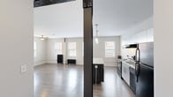 Located at 310 W Sixth St in Royal Oak, Michigan, this efficiently designed unit blends industrial character with contemporary updates. The open-plan kitchen and living area serves as the heart of the space, where a striking black steel structural column adds an industrial accent. The kitchen is well-appointed with granite-topped counters, a center island with pendant lighting, white upper cabinetry, black appliances including a range, dishwasher, and refrigerator, and a stainless sink — all set on durable wood-look flooring that flows throughout. The living area is bright and airy, illuminated by multiple windows dressed with blinds that invite natural light. A ceiling fan provides additional comfort, while cast-iron radiators lend a charming, historic character to the space. The bathroom features full-height, large-format slate-toned ceramic tile in the tub/shower surround, offering a clean and modern aesthetic. A dedicated closet provides practical storage. The neutral palette of warm whites and grays creates a cohesive, move-in-ready atmosphere. Situated in the vibrant Royal Oak community, this unit offers a functional and stylish living environment.