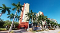 This residence is located within a prominent high-rise development that makes an immediate visual impression from the outside. The building's exterior showcases a vibrant combination of bold red and warm yellow tones, characteristic of South Florida's tropical architectural style. Towering palms line the entrance, creating a lush, resort-like approach that sets the tone for the property. A clearly marked signage at the entrance identifies the development as an Intracoastal Five Star Rental community, signaling a well-established and professionally managed property. The building rises dramatically against a clear blue sky, offering residents the potential for sweeping elevated views. The development appears to consist of multiple towers, contributing to a sense of scale and community. Unfortunately, interior imagery was not sufficiently illuminated to allow for detailed documentation of the unit's individual rooms or finishes. Based on the exterior presentation and the caliber of the development, the property is consistent with a well-appointed coastal residence. The surrounding landscape, architectural character, and building height together suggest a dynamic living environment that captures the energy and aesthetic of South Florida living.