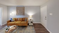 This single-floor, one-bedroom, one-bathroom unit is thoughtfully laid out to maximize functionality across its compact footprint. Dark hardwood-style flooring runs consistently throughout the space, providing a warm, cohesive aesthetic that ties each area together. Neutral gray walls serve as a versatile backdrop across all rooms.

The living area near the entry features clean lines and is bright and welcoming, with room for comfortable seating. Adjacent to it, a dedicated dining nook accommodates a round table for four and is equipped with a ceiling fan and a window that brings in natural light.

The galley-style kitchen is efficiently designed with white cabinetry, granite-look countertops, a double stainless steel sink, and black appliances including a range, microwave, refrigerator, and dishwasher, providing ample storage and prep space.

The bedroom is generously sized for the unit's footprint, featuring a ceiling fan with light, a mirrored sliding-door closet, and a window for natural light. Decorative wall panels add a stylish touch.

The bathroom includes tile flooring set in a diagonal pattern, a tiled tub-shower combination, a window for ventilation, and a vanity with granite-look countertops.